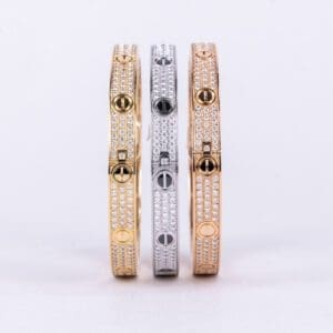 Three diamond-encrusted bangles in different metals.