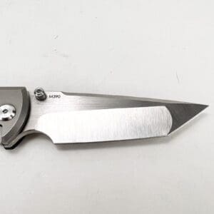 Silver folding knife blade on white background.