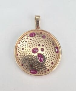 Gold pendant with red gemstone accents.