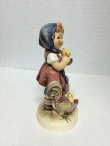 Figurine of girl with chicks and rooster.