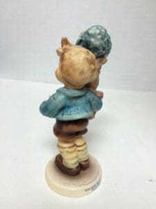 Child figurine holding a small animal.