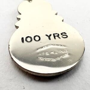 Snowman-shaped metal tag, "100 YRS" engraved.