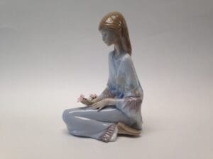 Porcelain figurine of woman holding flowers.