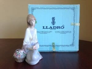 Lladro figurine with box on wooden table.