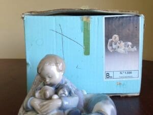Boy figurine with puppies beside blue box.