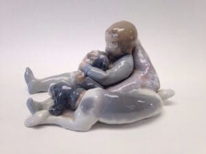 Child hugging dog porcelain figurine.