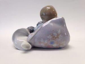 Porcelain figurine of child and dog resting.