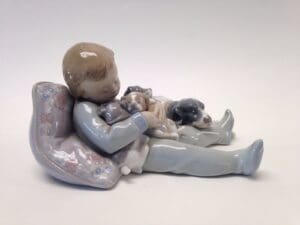 Child figurine with puppies and pillow.