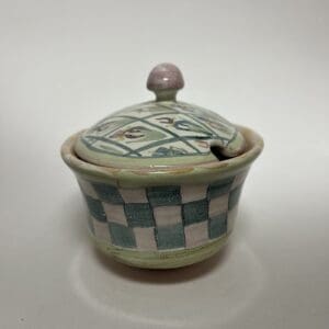 Ceramic container with lid and checkered pattern.