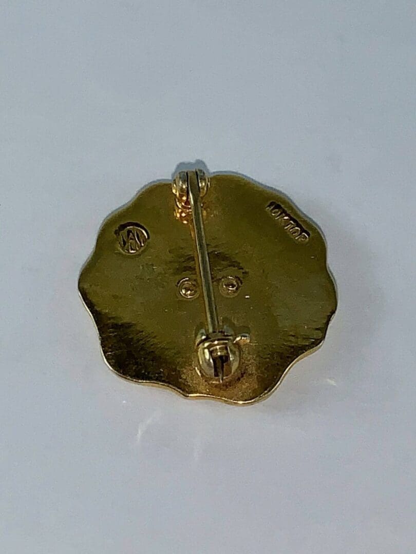 Gold brooch back with pin and markings.