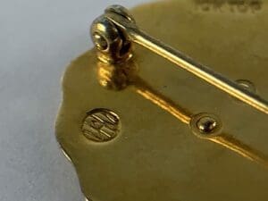 Gold brooch with intricate hinge detail.