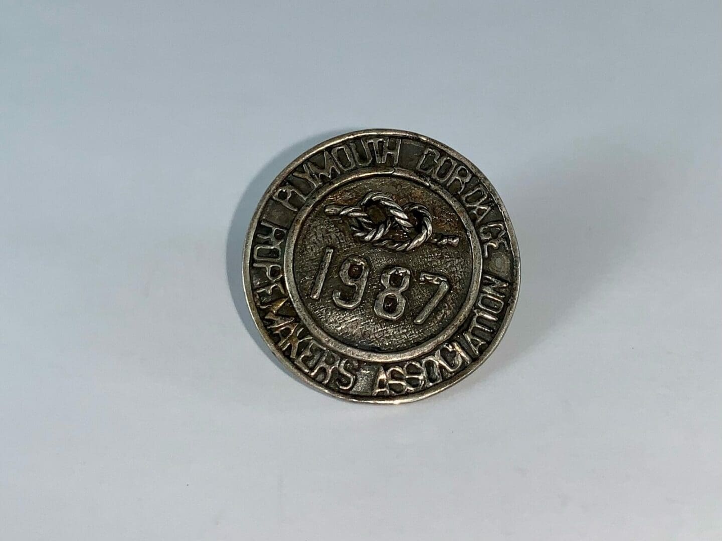 Round metal badge with "1987" engraving.
