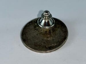 Metallic screw on a flat round base.