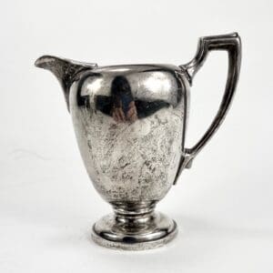 Silver vintage pitcher with ornate handle.