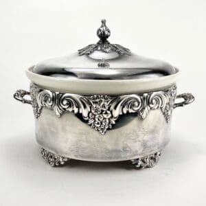 Ornate silver tureen with decorative handles.