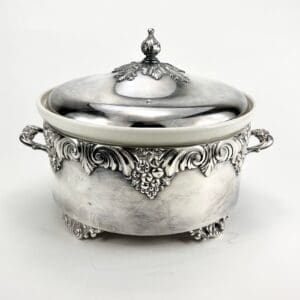 Ornate silver tureen with decorative handles.