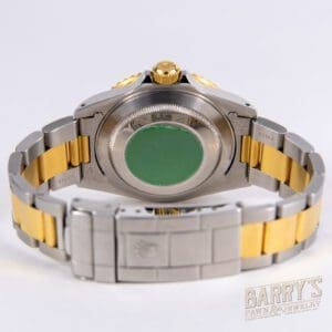 Two-tone wristwatch with clasp and green sticker.