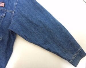 Denim jacket sleeve with small flag patch.