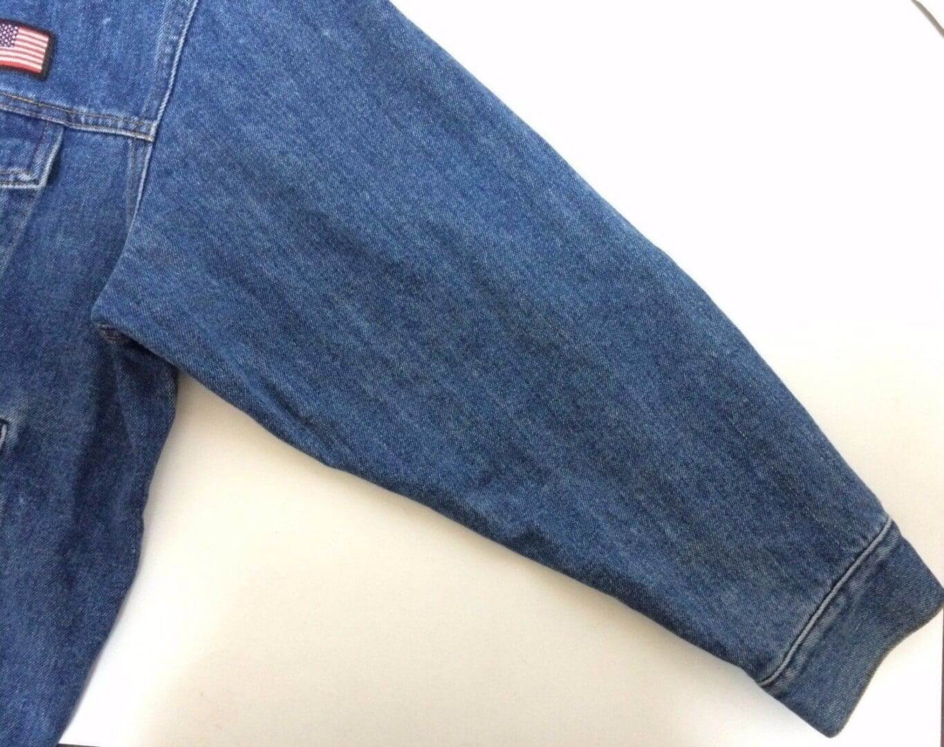 Denim jacket sleeve with small flag patch.