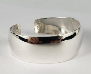 Silver cuff bracelet on white background.