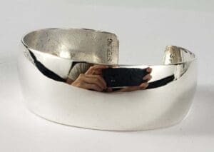 Silver cuff bracelet with reflective surface.