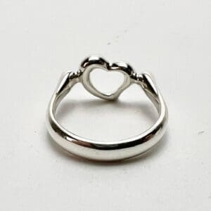 Heart-shaped silver ring on white background.