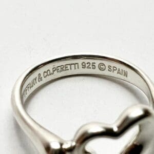 Silver ring engraved with brand and hallmark.