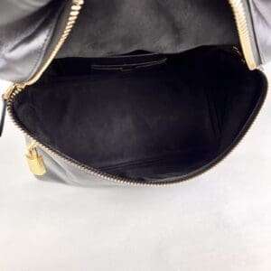 Open black leather handbag with gold zipper.