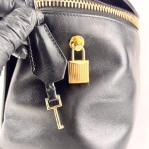 Black leather bag with gold lock and key.