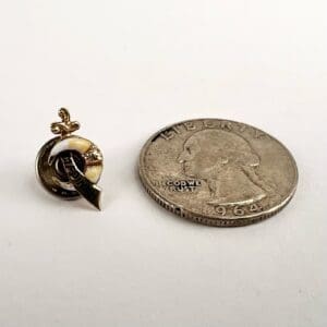Pin beside 1964 quarter on table.