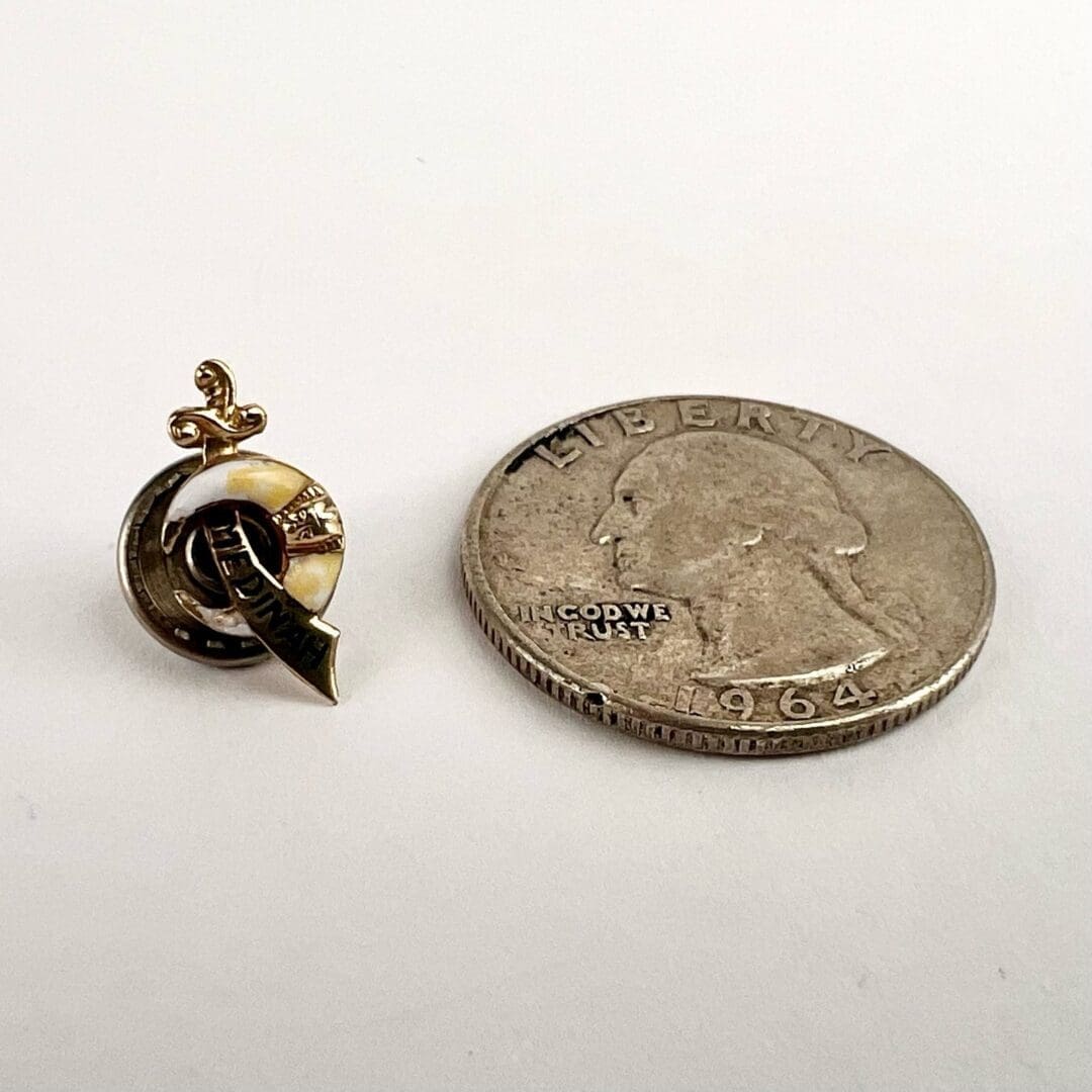 Pin beside 1964 quarter on table.
